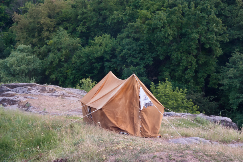 The old orange tent on a rock against the backdrop of the forest The old orange tent on a rock against the backdrop of the forest